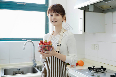 厨房里吃草莓的女性图片
