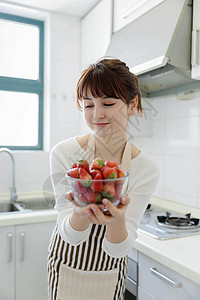 厨房里吃草莓的年轻女性图片