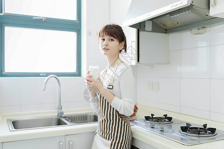 厨房里喝牛奶的年轻女性背景图片