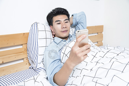 青年男性起床床上玩手机背景图片