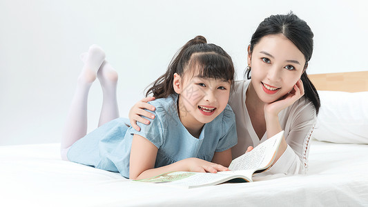 蓝色读书母亲节青年母女床上阅读背景