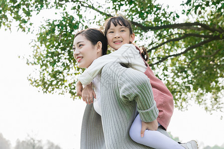 背着孩子的妈妈妈妈背着女儿游玩背景