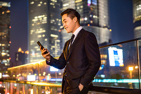 人像夜景素材年轻商务男子天桥玩手机背景