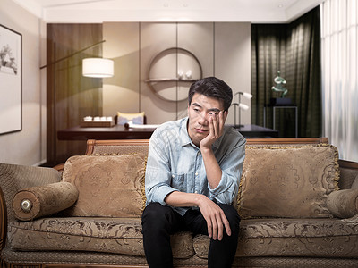 青年男性客厅沙发玩手机沉思的男性设计图片