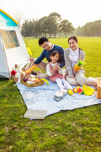 小女孩在旅游一家人欢乐地在草坪野餐背景