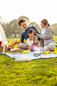 小女孩在旅游一家人欢乐地在草坪野餐背景