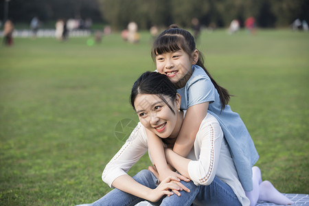 女儿和妈妈草地上玩耍背景图片