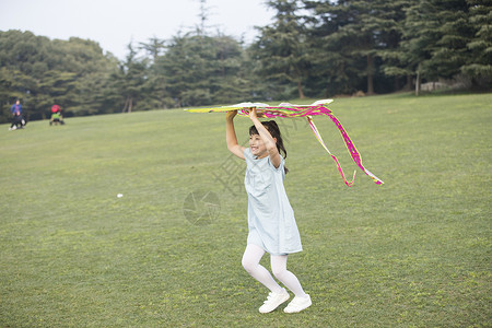 小女孩拿着风筝在草坪上奔跑图片