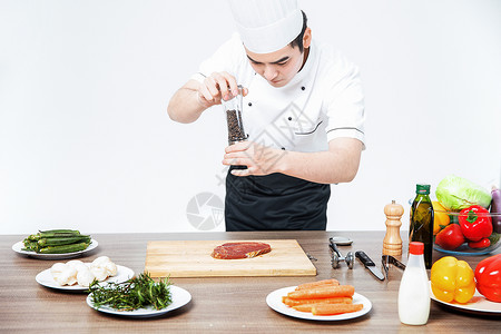 男性职业餐饮西餐厨师牛排撒黑胡椒背景