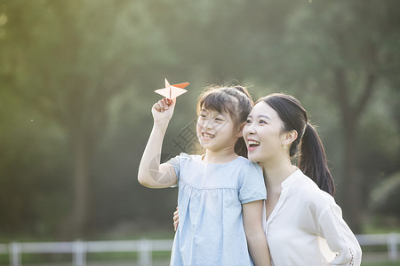 童年纸飞机妈妈和女儿在草坪上玩纸飞机背景