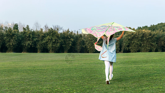 笑容阳光女孩在草坪玩风筝背景