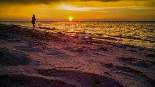 日落时分在沙滩上散步的人背景图片