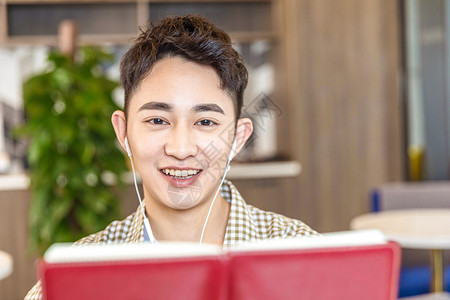 青年男性戴耳机看书背景图片