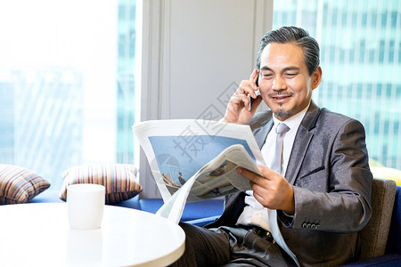 商务男性看报纸打电话图片
