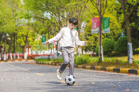 小男孩放学踢足球背景图片