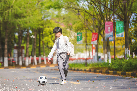 小男孩放学踢足球背景图片
