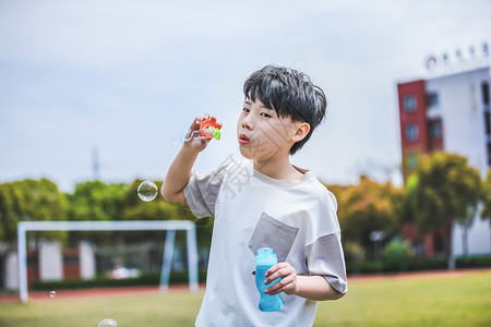 小男孩操场吹泡泡背景图片