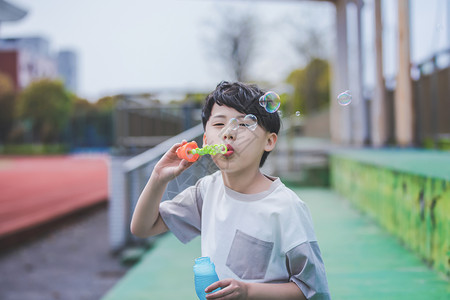 小男孩操场吹泡泡背景图片