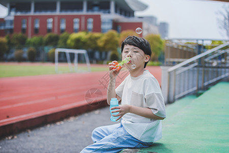 小男孩操场吹泡泡背景图片