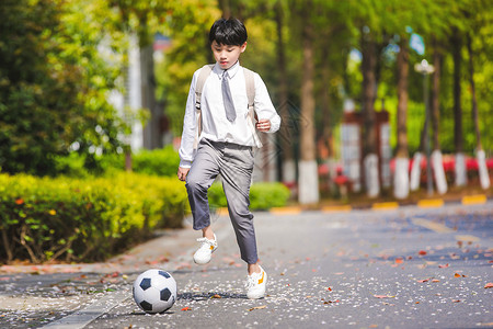 活力背书包小学生放学踢足球背景