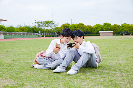 两个手机小学生操场玩手机背景