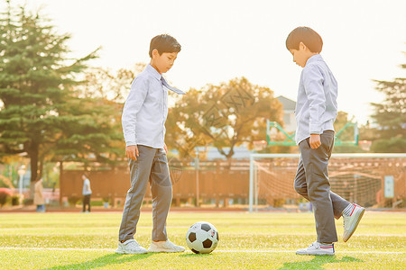 小学生操场踢足球背景图片