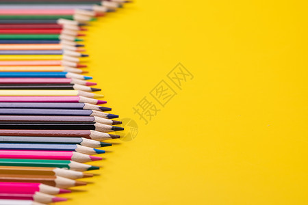 色彩素材桌面一堆彩铅排列在黄色背景上背景