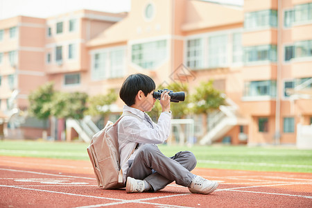 儿童摄影师小学生在操场上拿望远镜观望背景