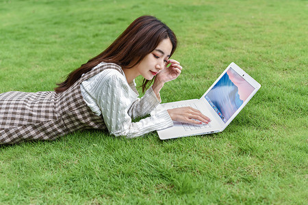 草地上玩电脑的女生图片