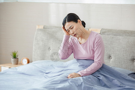 中年女性失眠头痛坐在床上背景图片