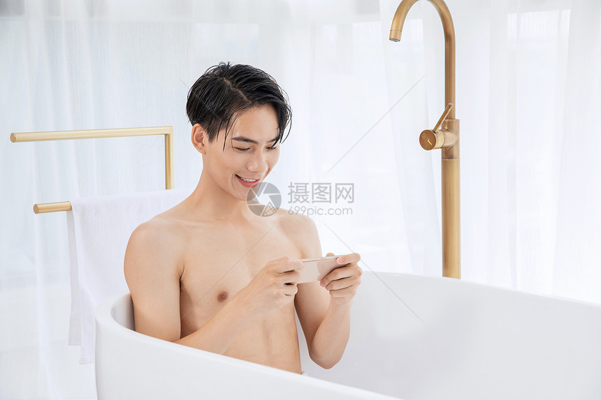 年轻男子泡澡玩手机图片