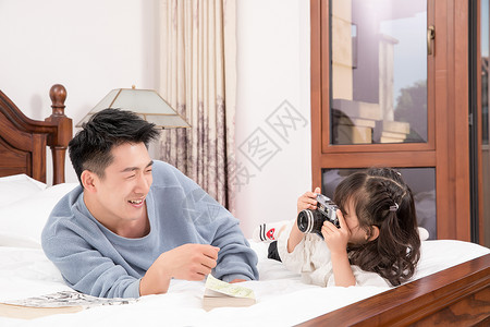 小女孩拿相机给爸爸拍照图片