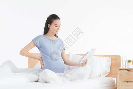 坐着的母亲孕妇坐床上看书背景