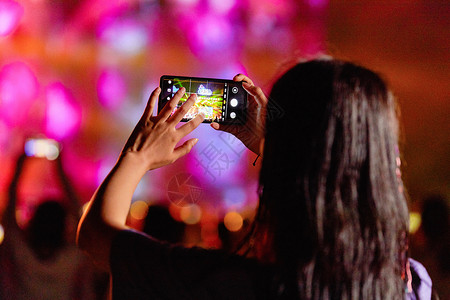 海边人群背影潮流美女用手机在音乐节拍照背景