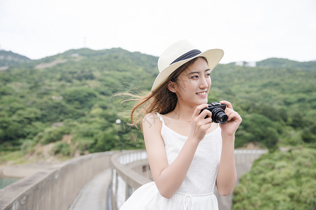 手持相机拍照的夏日度假美女清新美女海岛拍照背景