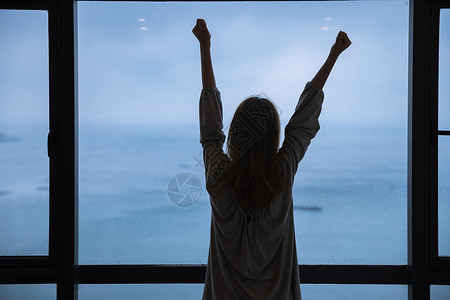 年轻女性伸懒腰海边雨天年轻女性起床背景