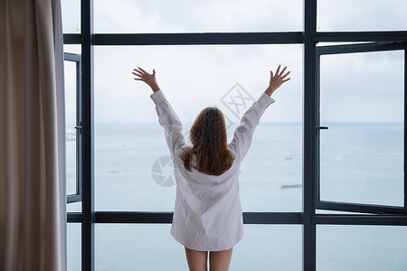 起床的女孩年轻女性窗边伸展背影背景