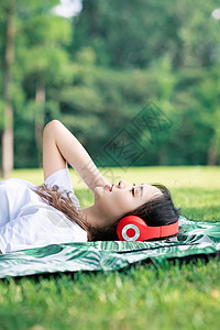 躺在草地的女人躺在草地上听音乐背景