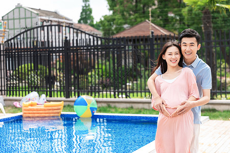 微笑有爱孕妇和丈夫在户外游泳池拥抱背景