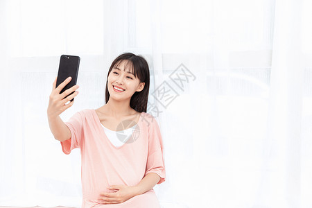 孕妇在客厅纱窗旁边使用手机自拍背景图片