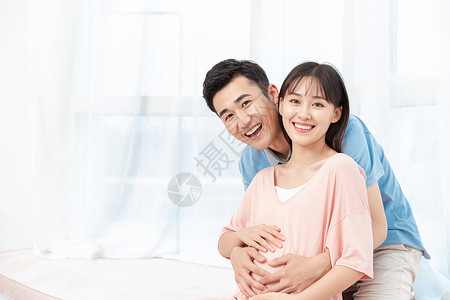一个温暖微笑准爸爸摸着准妈妈肚子呵护孕妇背景