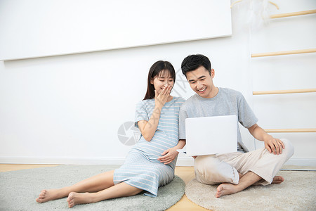 孕妇电脑孕妇和丈夫一起在卧室地毯上看电脑背景
