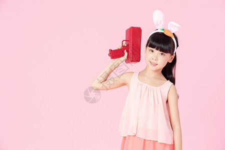 可爱小女孩戴着兔耳朵拿着玩具枪背景图片