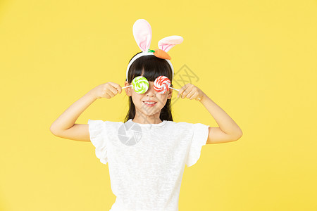 戴着兔耳朵的小女孩拿着糖果图片