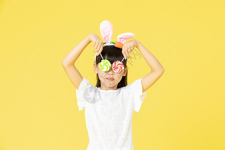 戴着兔耳朵的小女孩拿着糖果背景图片