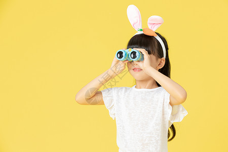 戴着兔耳朵的小女孩用望远镜看向远方图片