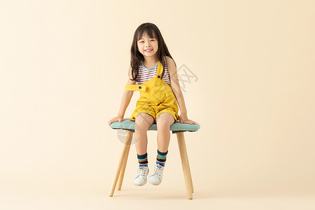 可爱小女孩乖巧坐在椅子上背景图片