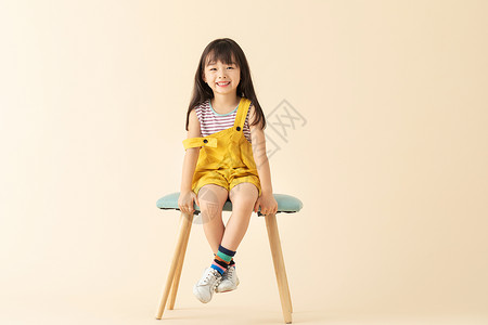 可爱小女孩乖巧坐在椅子上图片