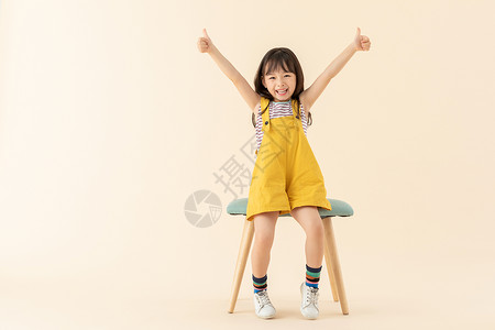 小女孩坐在椅子上微笑点赞高清图片