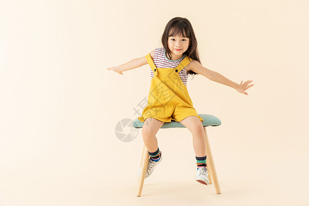 小女孩坐椅子上伸开双手背景